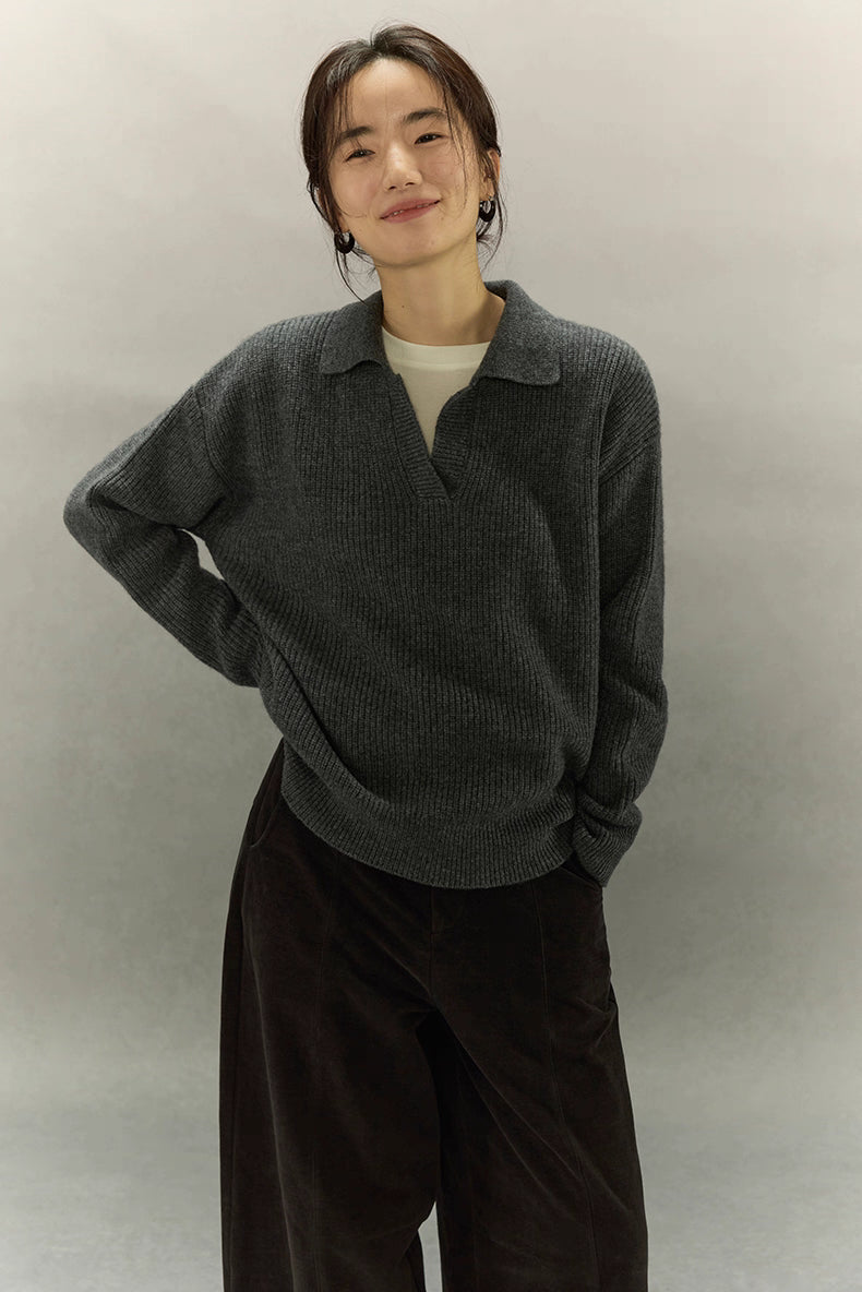Model smiling in charcoal gray ribbed cashmere-wool polo sweater, relaxed fit with drop shoulders.
