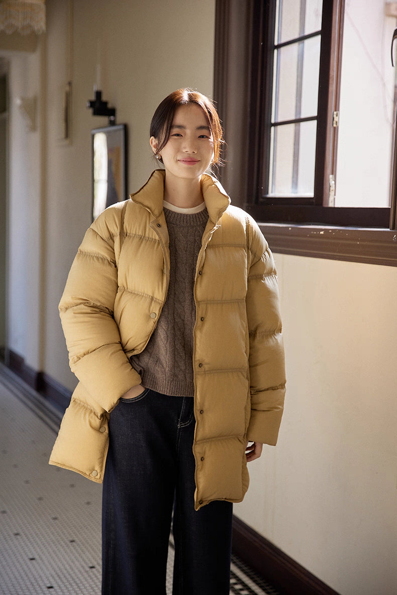 Woman wearing caramel brown Cloud-Contour Down Coat, full-length front view in hallway, hands in pockets