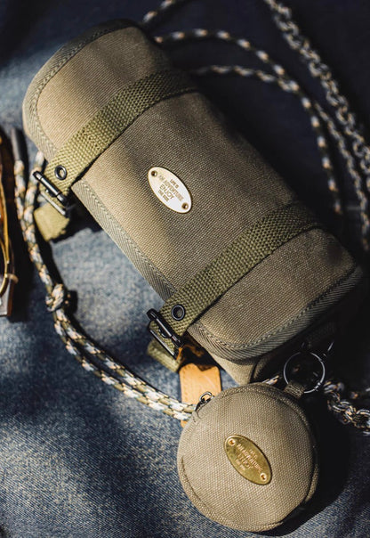 Olive canvas tool roll crossbody bag and coin pouch displayed on denim fabric