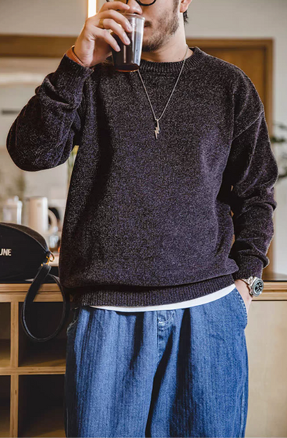 Man wearing dark purple chenille sweater holding a cup of coffee in a casual indoor scene