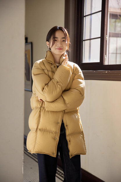 Cozy portrait of woman in caramel brown Cloud-Contour Down Coat, standing by window with arms crossed