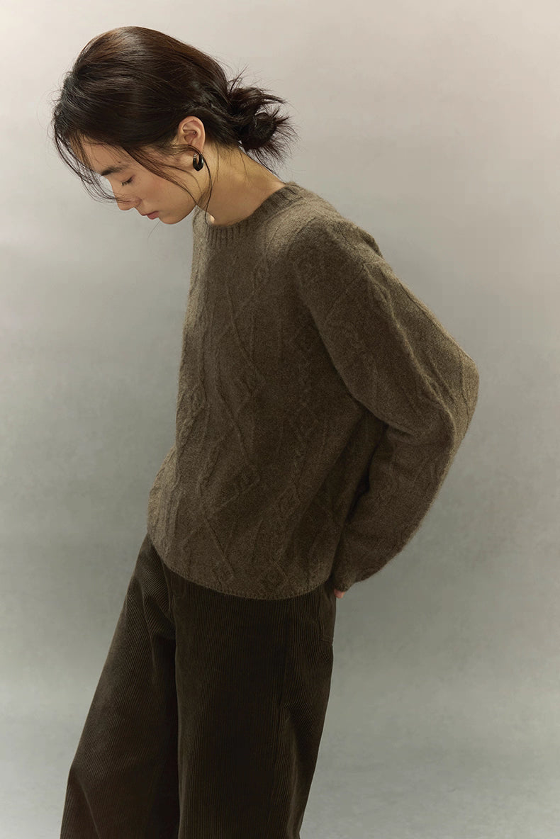 Side profile of yak wool sweater highlighting relaxed fit and intricate diamond cable weave.