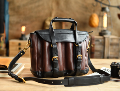 Two-tone Italian leather field-style camera bag on wooden desk with warm light