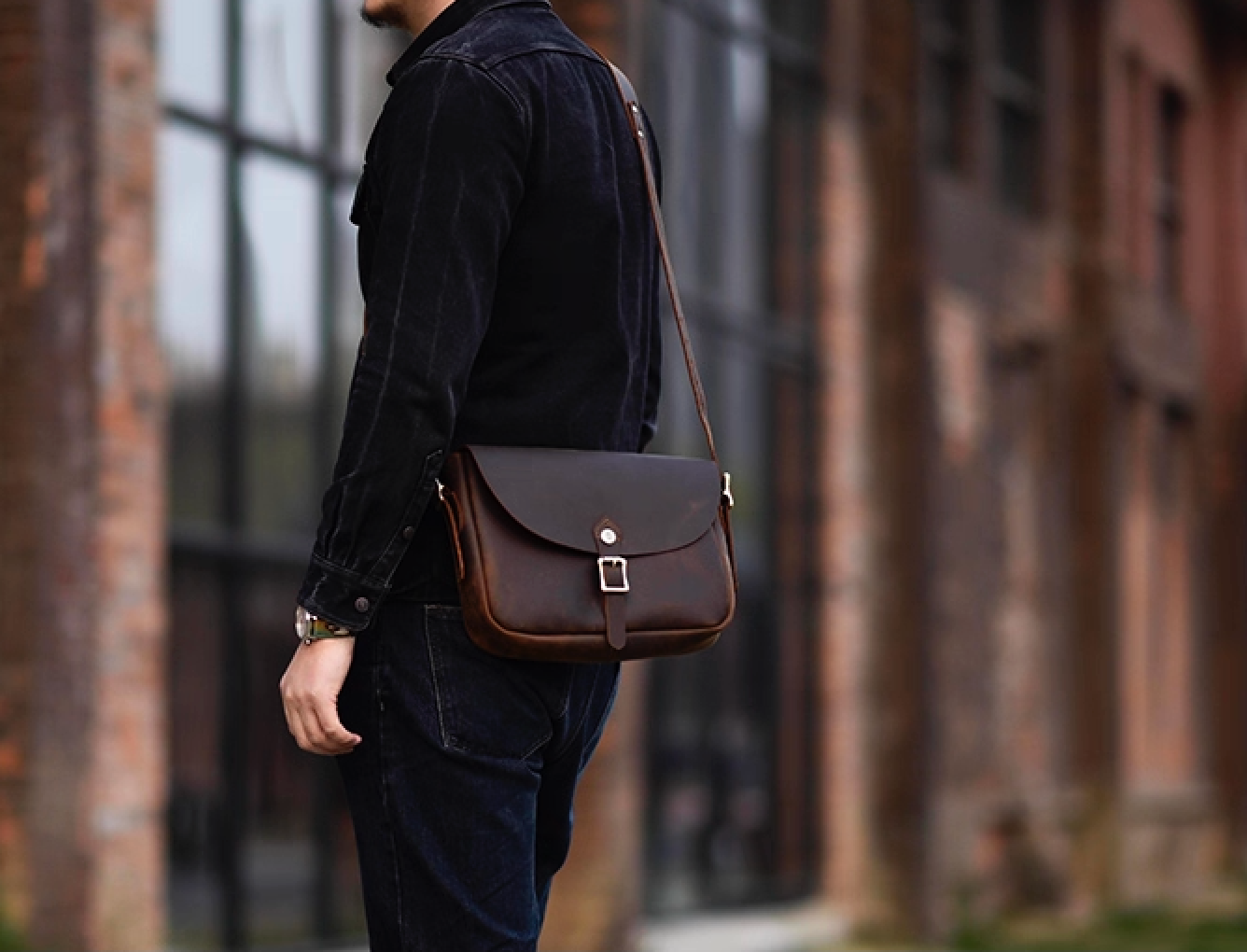 Man wearing the dark brown Italian leather messenger bag crossbody in an urban outdoor setting.