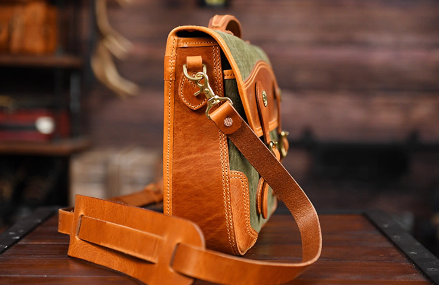 Side profile highlighting leather strap and stitched details of waxed canvas satchel