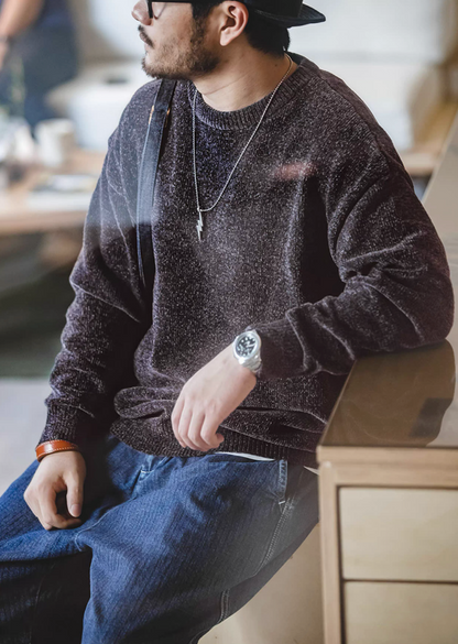 Model seated wearing dark purple chenille sweater with jeans in a cozy café setting