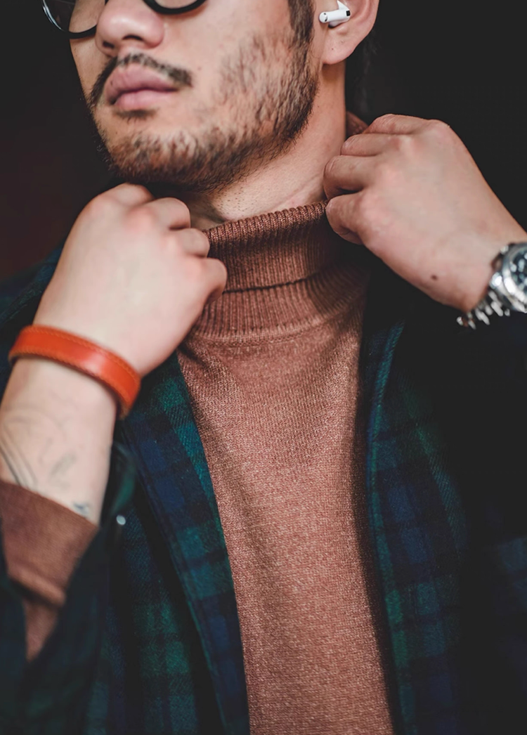 Close-up of man adjusting high collar of mocha brown turtleneck sweater
