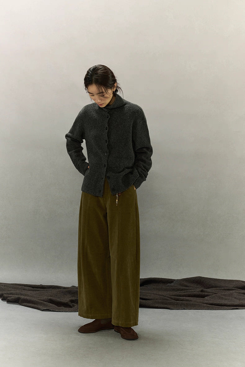 Full-body view of model wearing dark charcoal high-neck wool cardigan paired with olive wide-leg corduroy pants.