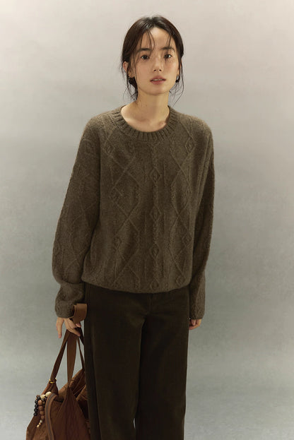Model holding brown tote bag while wearing yak wool diamond knit sweater, full front pose