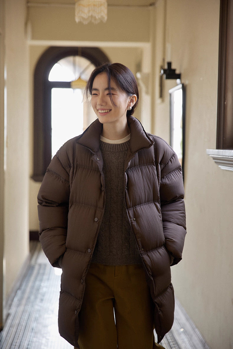 Front view of dark coffee brown Cloud-Contour Down Coat, woman smiling in hallway