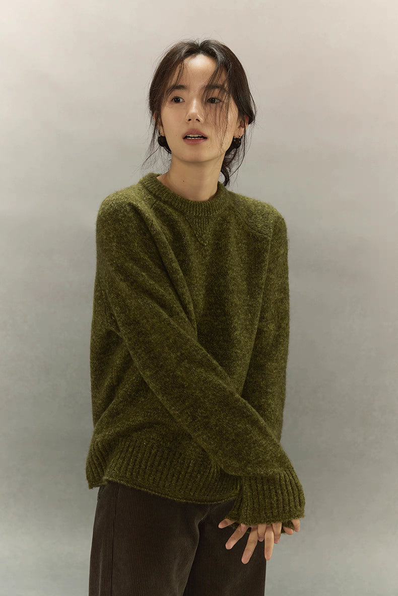 Front view of woman wearing moss green cashmere blend sweater, showing relaxed silhouette.