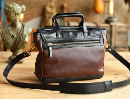 Rear view of brown and black leather camera bag showing gold zipper and strap