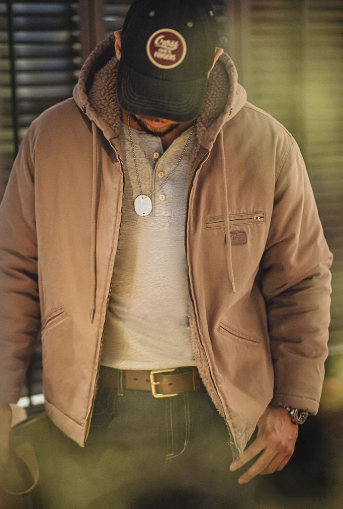 Man wearing khaki sherpa-lined jacket unzipped, layered with T-shirt