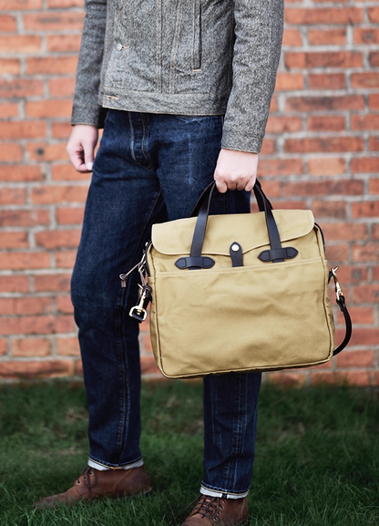 Man carrying khaki waxed canvas laptop briefcase by leather handles