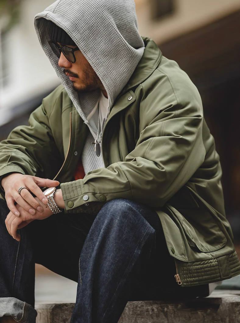 Model seated in Army green Flight Jacket 074 with hoodie layer