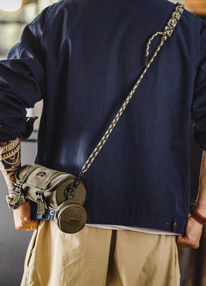 Rear view of olive canvas barrel crossbody bag worn over navy jacket