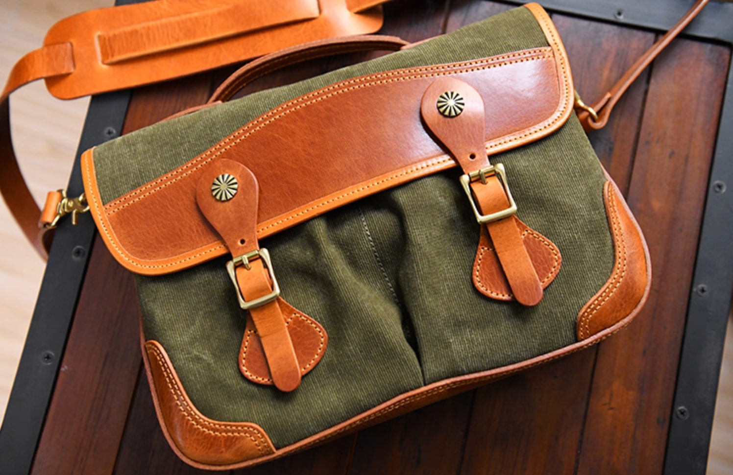Top-down view of vintage waxed canvas satchel on wooden table