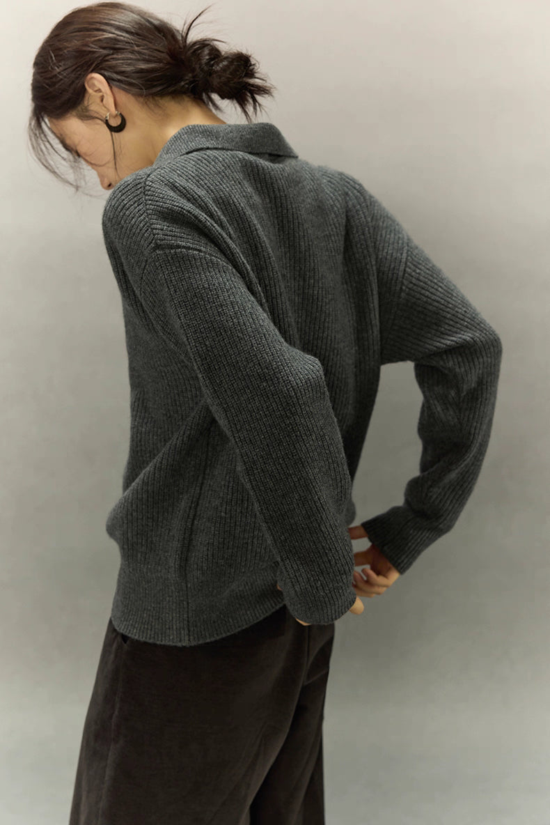 Angled back view showing soft ribbed texture and structured fit of the charcoal polo sweater.