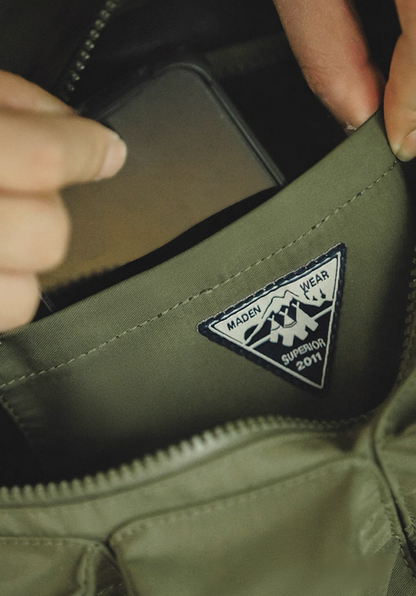 Inside view showing logo patch and phone pocket of army green crossbody bag