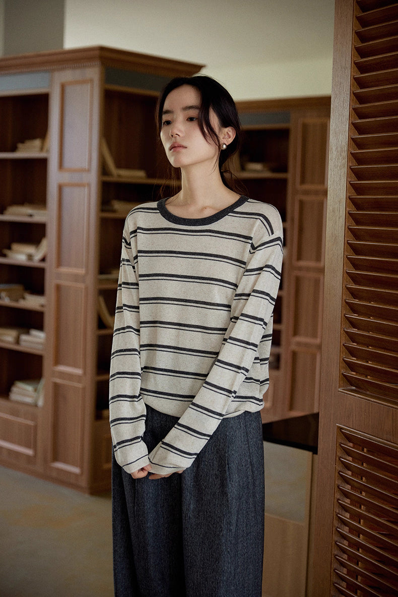 Close-up of oat and dark gray striped version of the Tencel-linen pullover in a calm indoor setting.