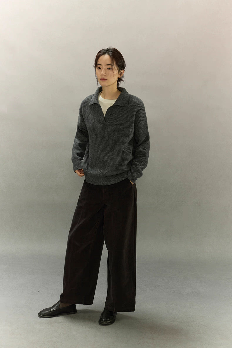 Model standing in full-length charcoal ribbed cashmere-wool sweater with minimal styling.