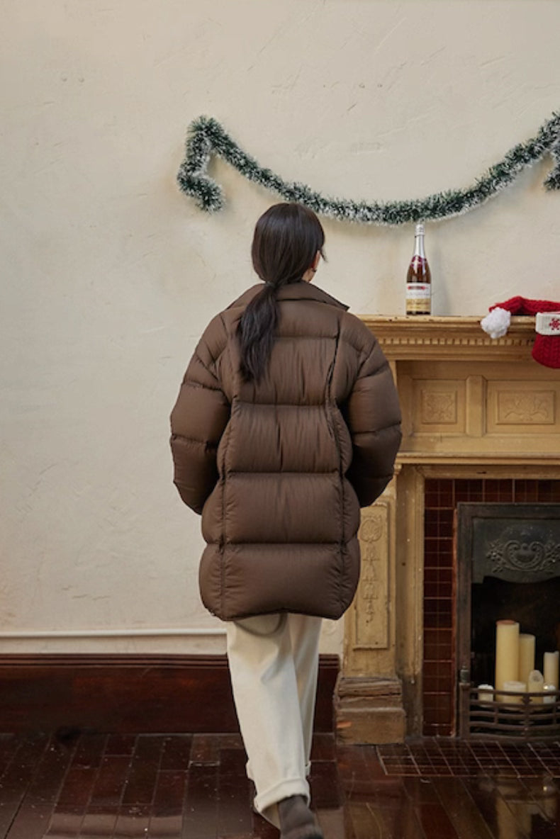 Back view of dark coffee brown Cloud-Contour Down Coat in living-room setting with fireplace decor
