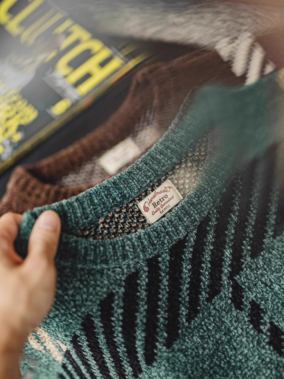 Flat lay of green and brown retro plaid chenille sweaters folded together