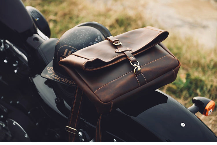 Brown leather satchel placed on a motorcycle seat showing rugged vintage style