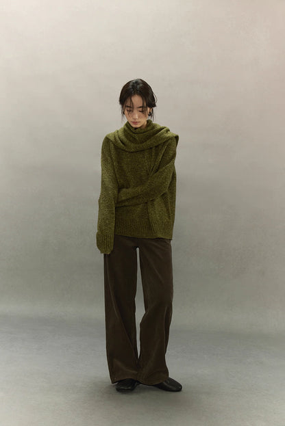 Full-length image of model wearing moss green sweater and wide-leg trousers, minimal winter outfit.