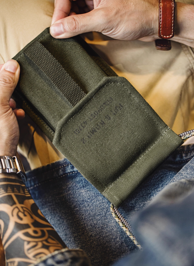 Close-up of hands holding M-16 Field Pouch Mini olive canvas bag