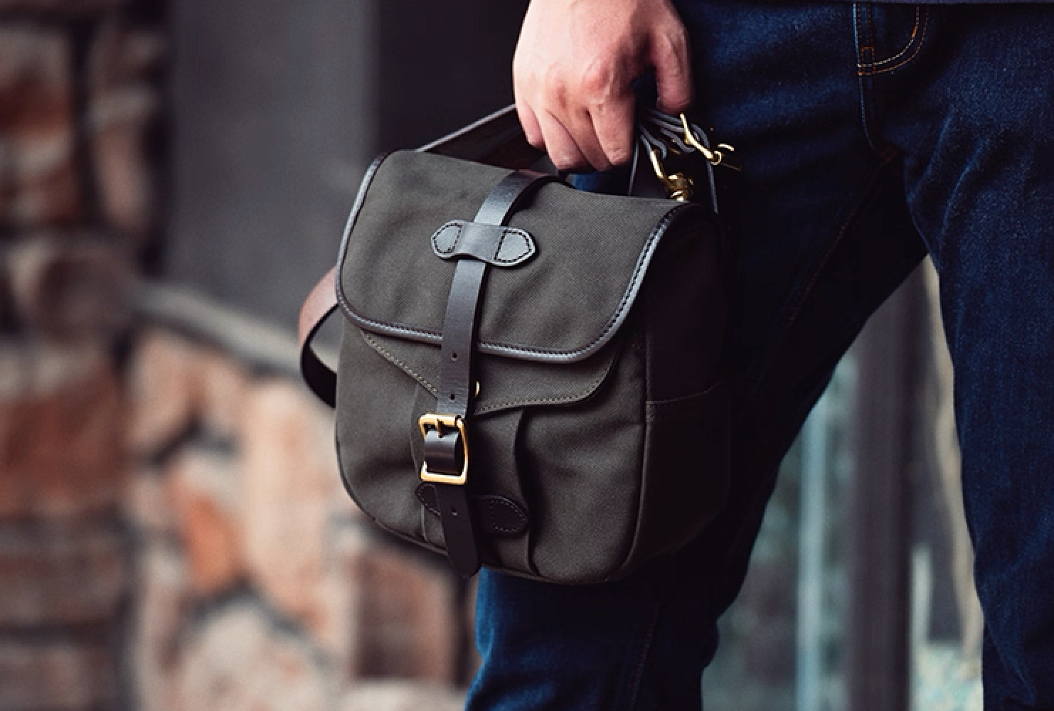 Olive Green Nomad satchel carried by hand, showcasing rugged outdoor style.