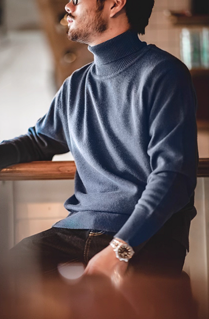 Man wearing dusty blue turtleneck sweater sitting casually at café counter