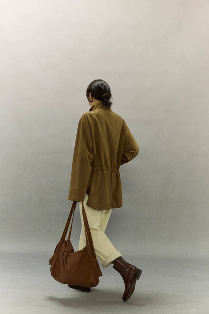 Model smiling while wearing caramel suede jacket with adjustable waist.