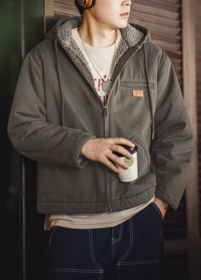 Man wearing dark green sherpa-lined jacket holding coffee cup