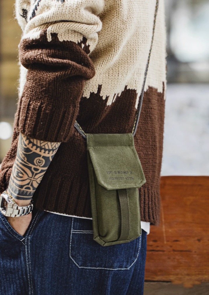 Model wearing olive canvas M-16 Field Pouch Mini with knit sweater and jeans