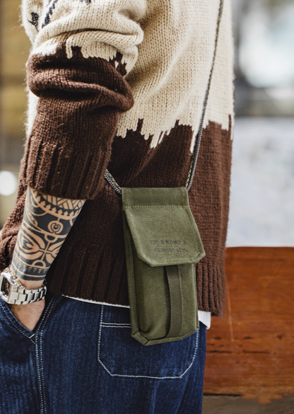 Model wearing olive canvas M-16 Field Pouch Mini with knit sweater and jeans