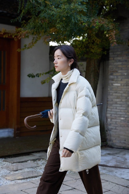 Outdoor side view of off white Cloud-Contour Down Coat as woman walks holding an umbrella
