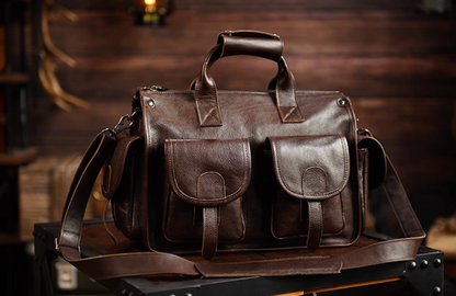 Front angle of dark brown full-grain leather work and travel bag with flap pockets