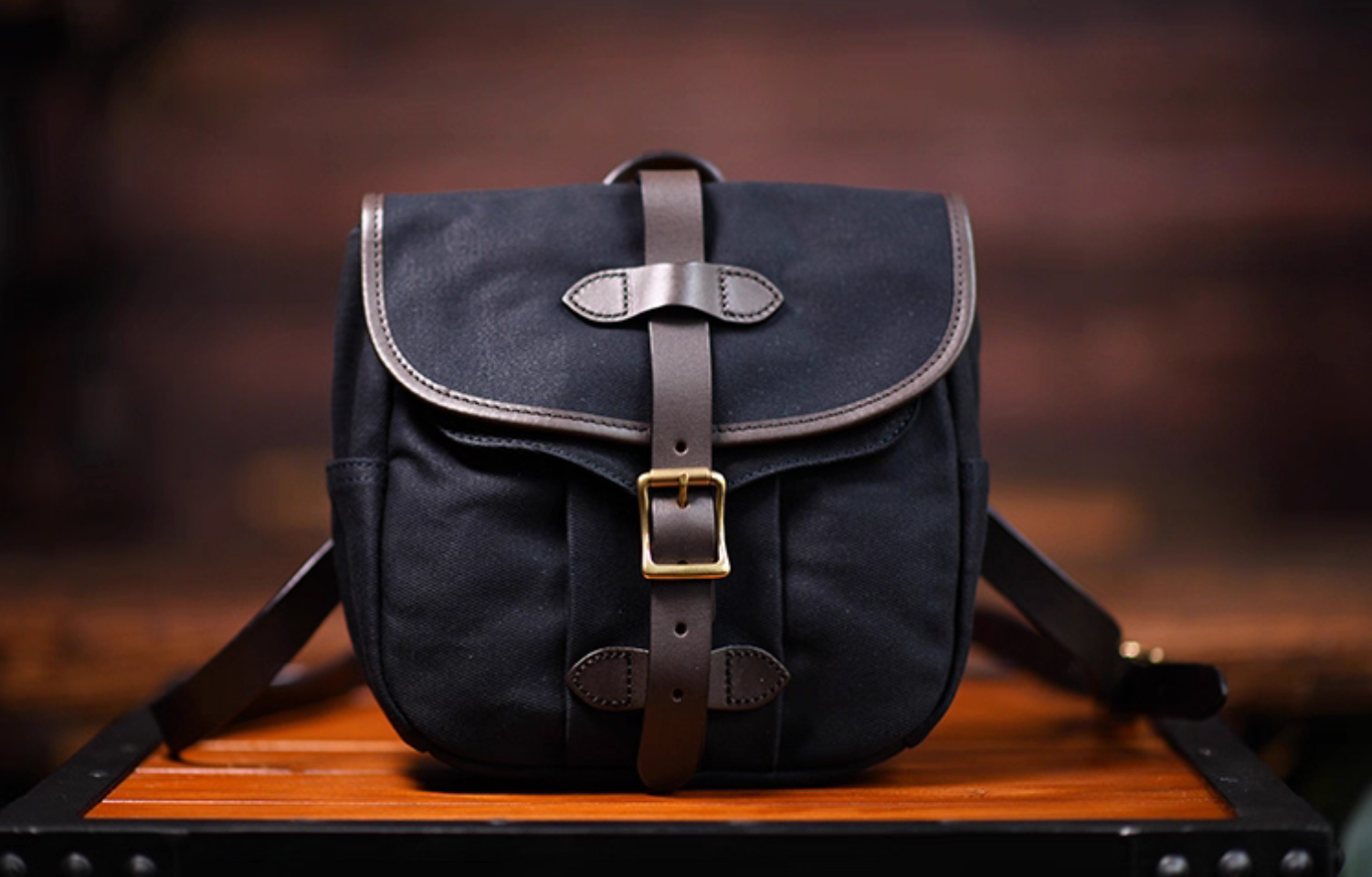 Front view of Nomad Charcoal Black waxed canvas satchel with leather strap and brass buckle.