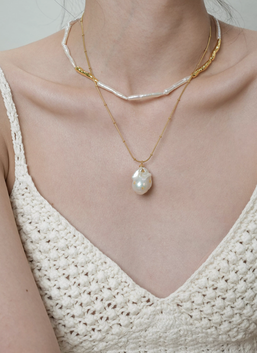 Model wearing layered baroque pearl gold accent choker necklace with pendant necklace showing pearl choker and gold chain combination