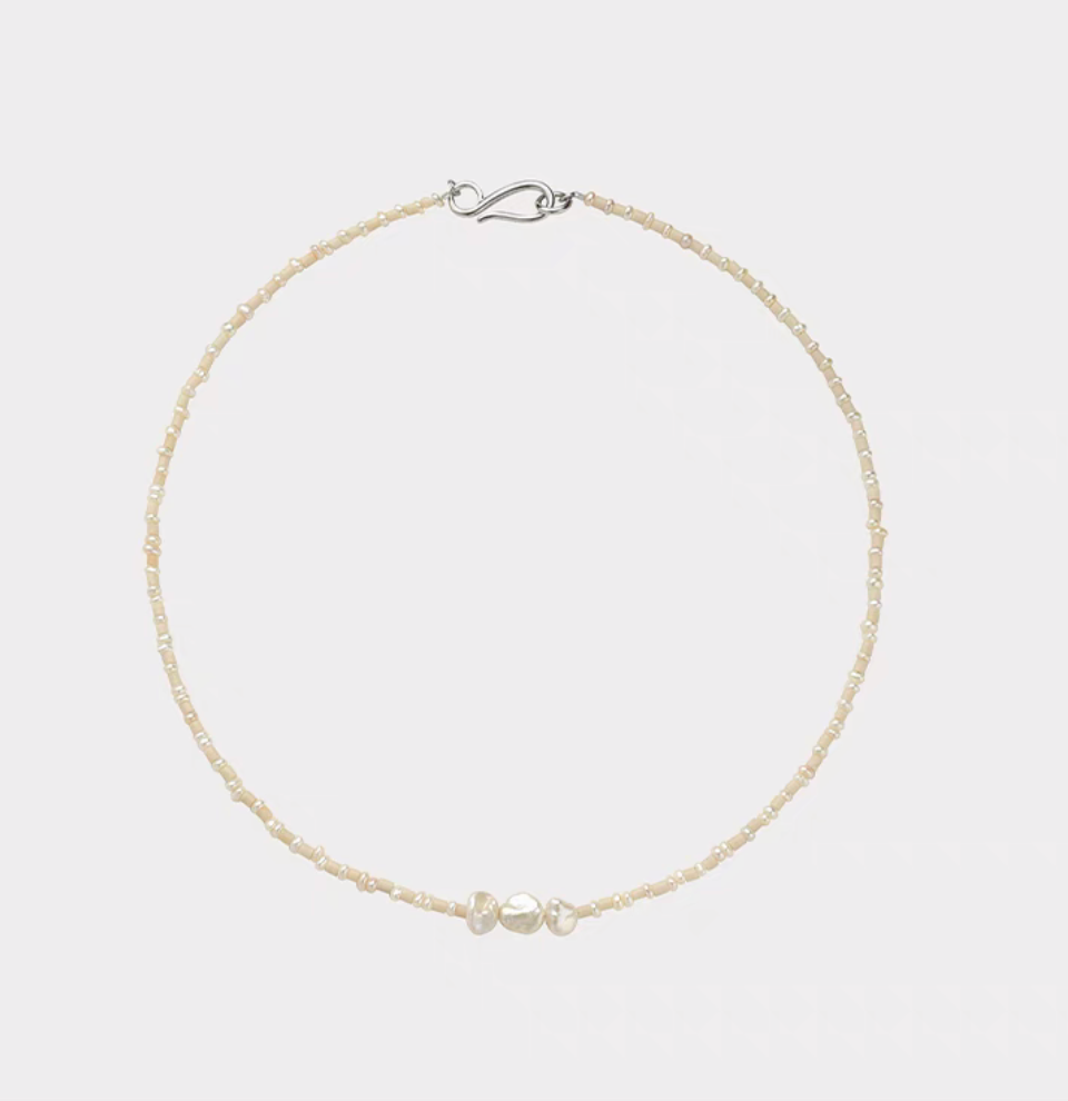 Baroque pearl and stone necklace flat lay featuring natural freshwater pearls with small stone beads and minimalist silver clasp