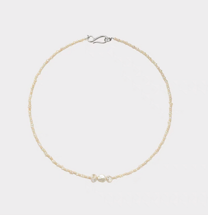 Baroque pearl and stone necklace flat lay featuring natural freshwater pearls with small stone beads and minimalist silver clasp