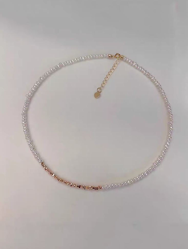 Delicate pearl strand necklace with gold-plated silver accents flat lay showing natural freshwater pearls with gold fragment details and adjustable chain