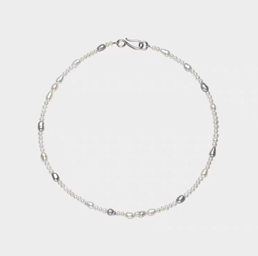 Elegant baroque pearl choker flat lay featuring irregular freshwater pearls in white and soft gray tones arranged on a minimalist silver chain