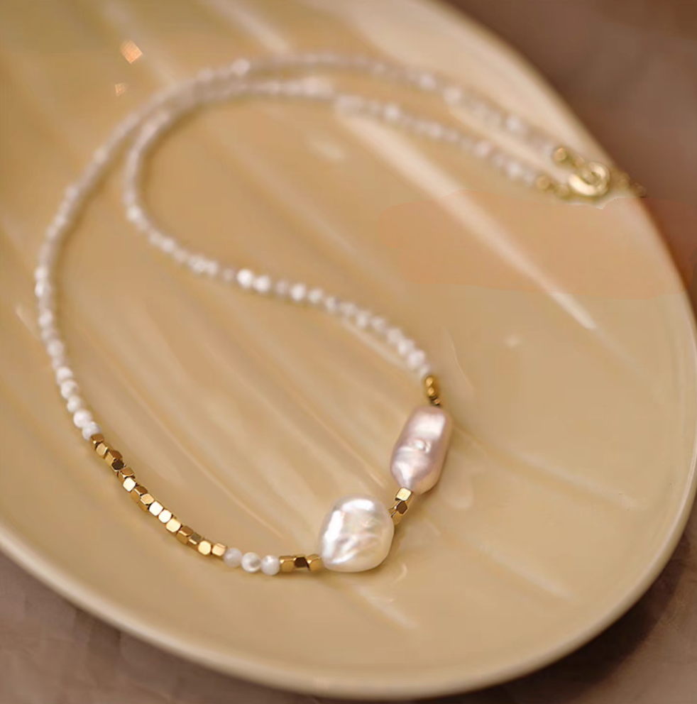 Heirloom pearl and shell beaded necklace flat lay on plate showing baroque pearls, small pearls, and gold beads