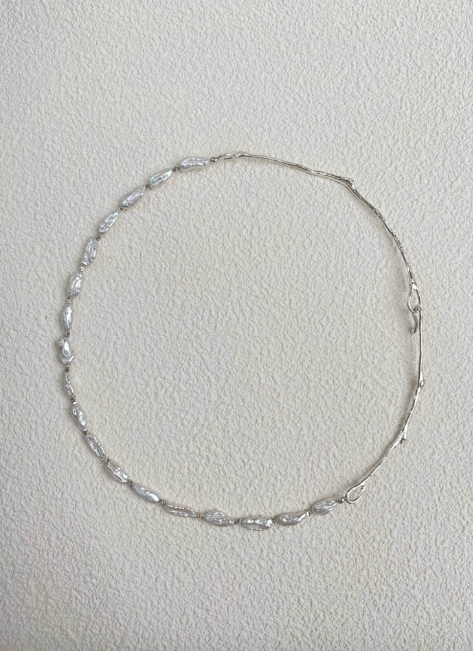 Nature’s Grace baroque pearl branch necklace full view on textured background showing asymmetrical pearl and silver branch design