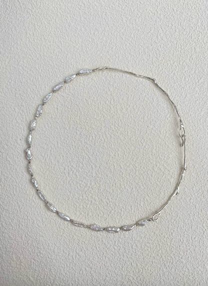 Nature’s Grace baroque pearl branch necklace full view on textured background showing asymmetrical pearl and silver branch design