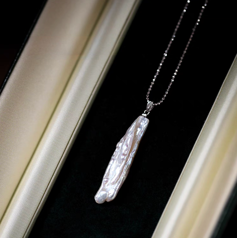 Organic baroque pearl drop necklace in silver displayed in black jewelry box featuring elongated irregular freshwater pearl pendant