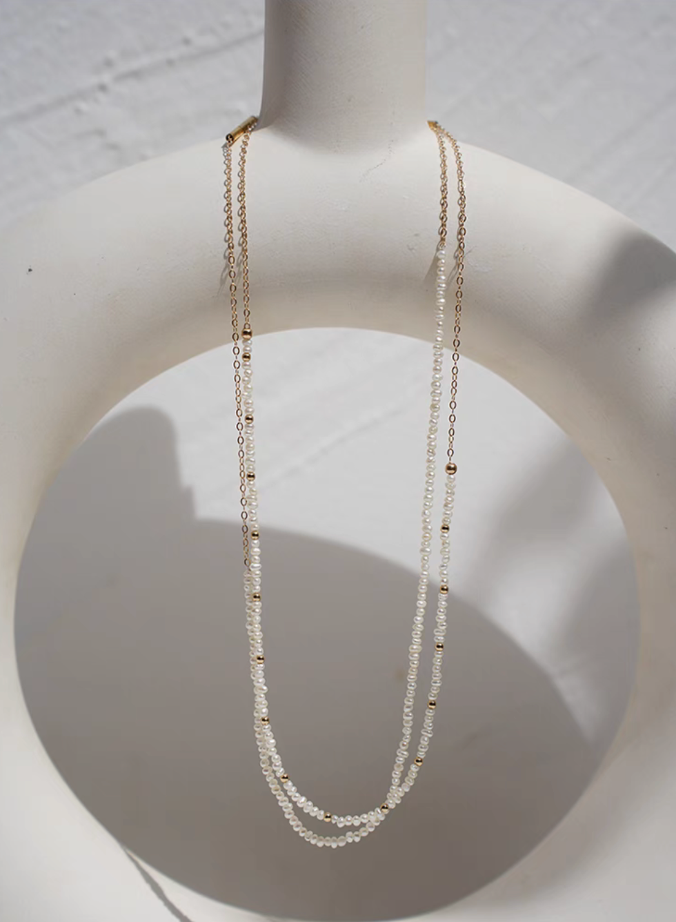 Rice pearl necklace with 14K gold-filled accents featuring Style A and Style B displayed together on jewelry stand with layered pearl and chain design