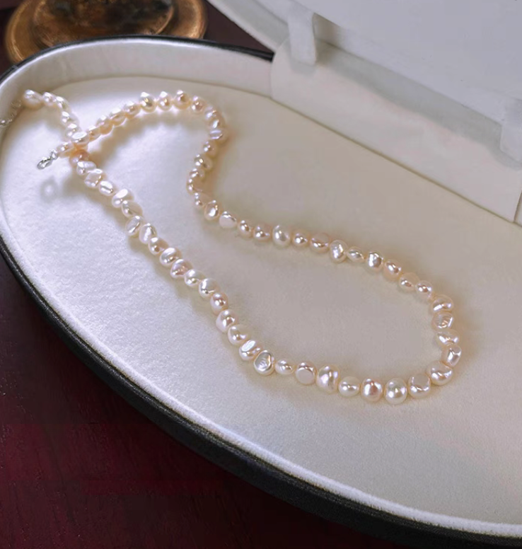 Timeless baroque pearl and silver necklace flat lay in jewelry box showing irregular freshwater pearls with natural organic shapes